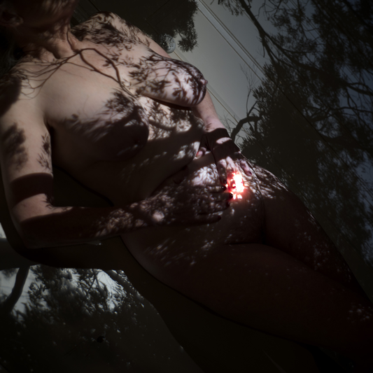 Artistic Nude showing a glowing red reflecting light behind a forest-like setting
